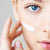 blue-eyed woman applies IUM organic rejuvenating cream on her face 
